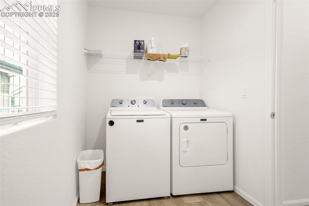 Image 24 of 38: Laundry room with separate washer and dryer, light wood-type flooring, and