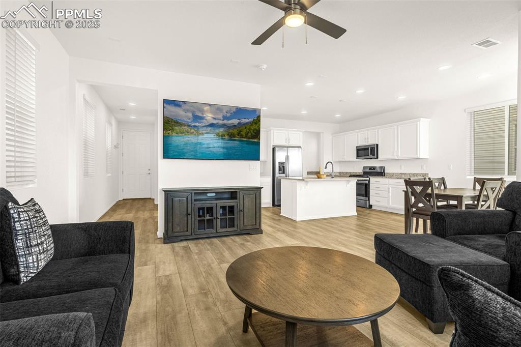 Image 7 of 38: Living area with light wood-style flooring, ceiling fan, and recessed light