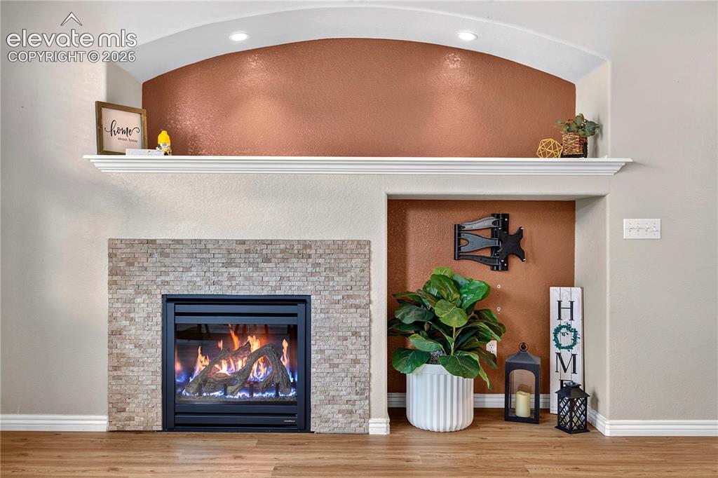 Image 17 of 43: Fireplace with stacked stone surround, integrated mantel, recessed arched d