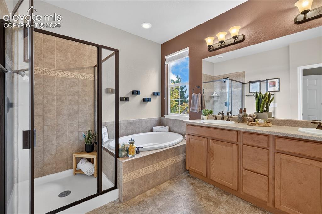 Image 30 of 43: Bathroom featuring a dual-sink vanity with wood cabinetry, a tiled-surround