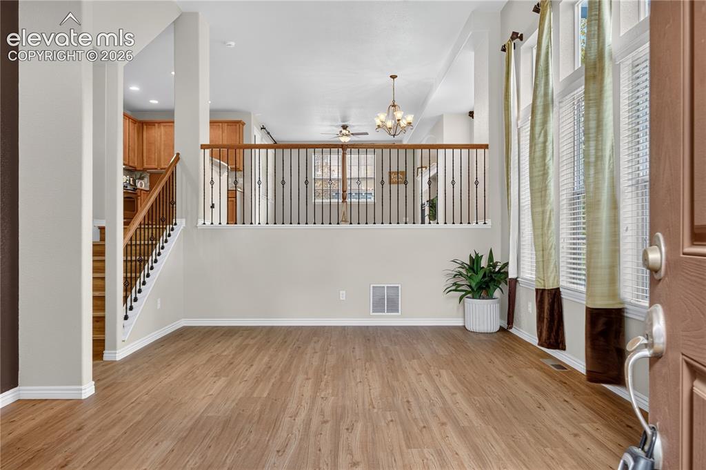 Image 7 of 43: Foyer featuring wood-finish flooring, two-story tall windows, and a metal s