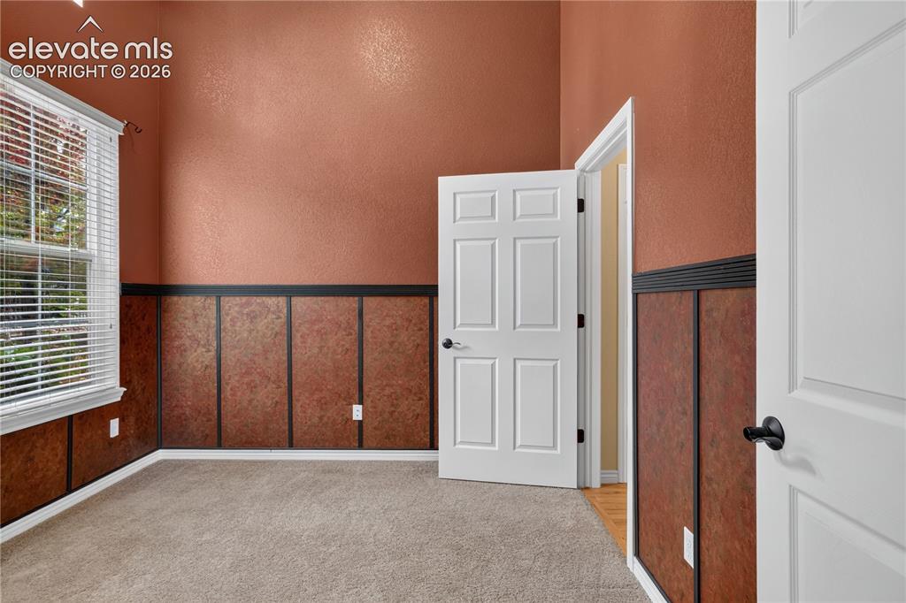 Image 9 of 43: Office - featuring high ceilings, textured wall paneling with chair rail, n