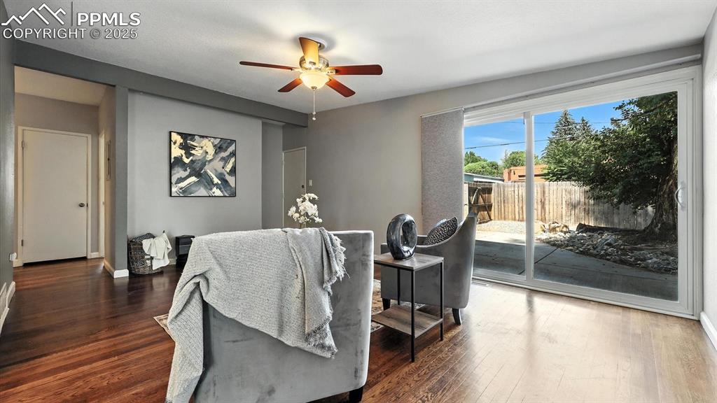 Image 14 of 35: The Living Room features wood flooring, a lighted ceiling fan, and slider t