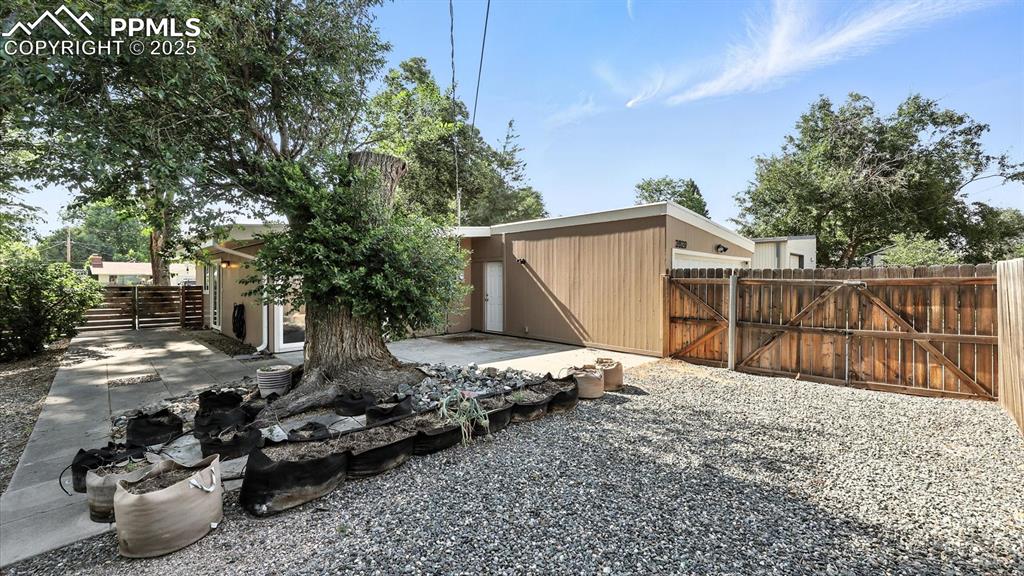 Image 16 of 35: Large xeriscaped yard with mature trees and shrubs.
