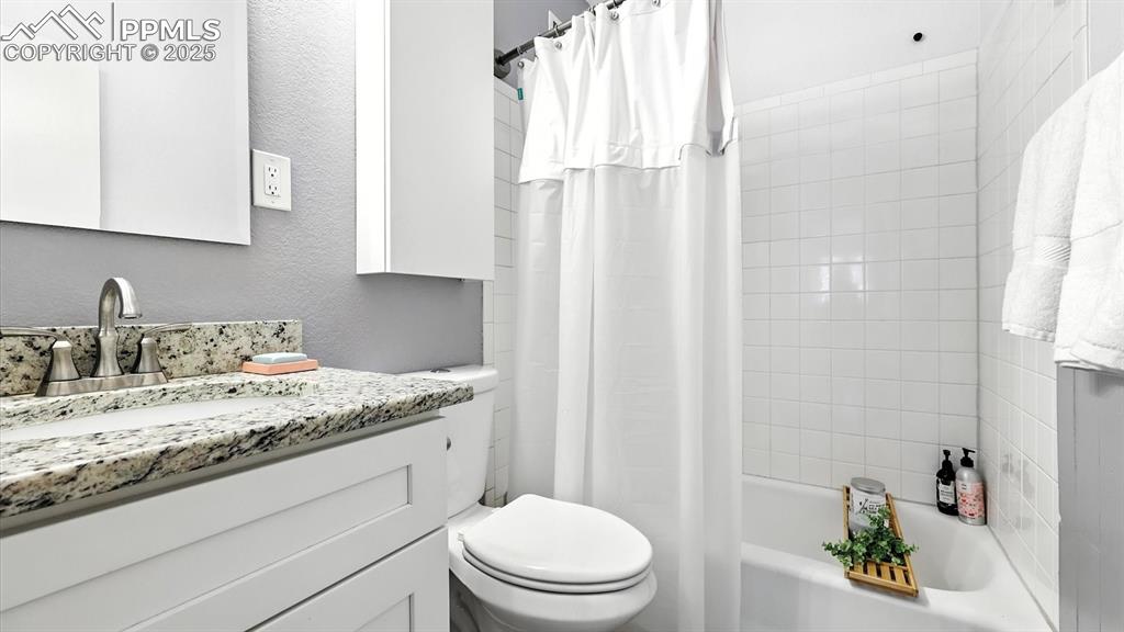 Image 27 of 35: Full Hall Bathroom with vanity, mirror, and tiled tub/shower.