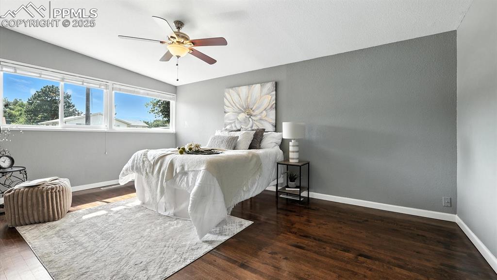 Image 30 of 35: The Primary Bedroom has wood flooring, a lighted ceiling fan, closet, and s
