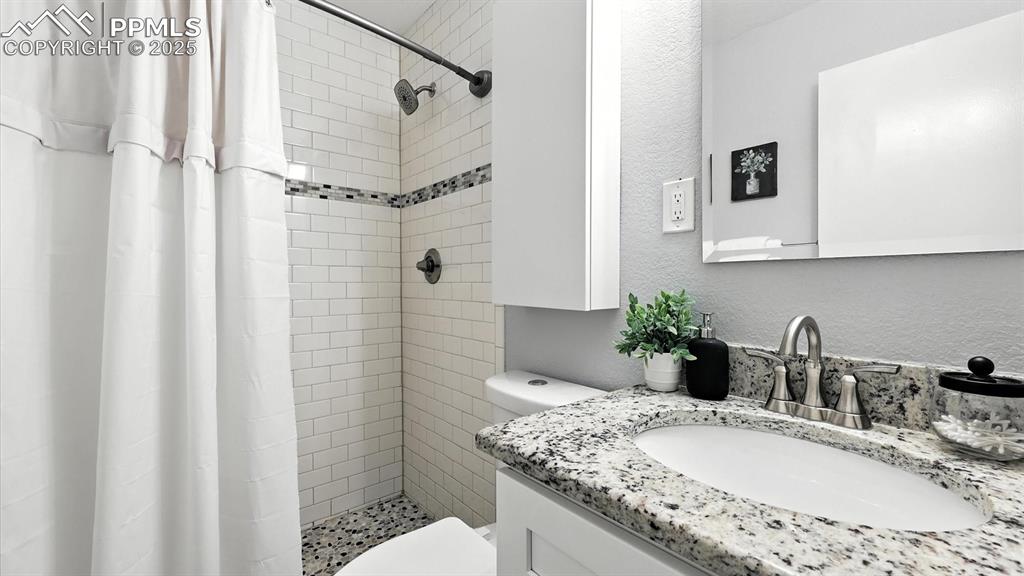 Image 32 of 35: Shower Bathroom with vanity, mirror, and tiled shower.