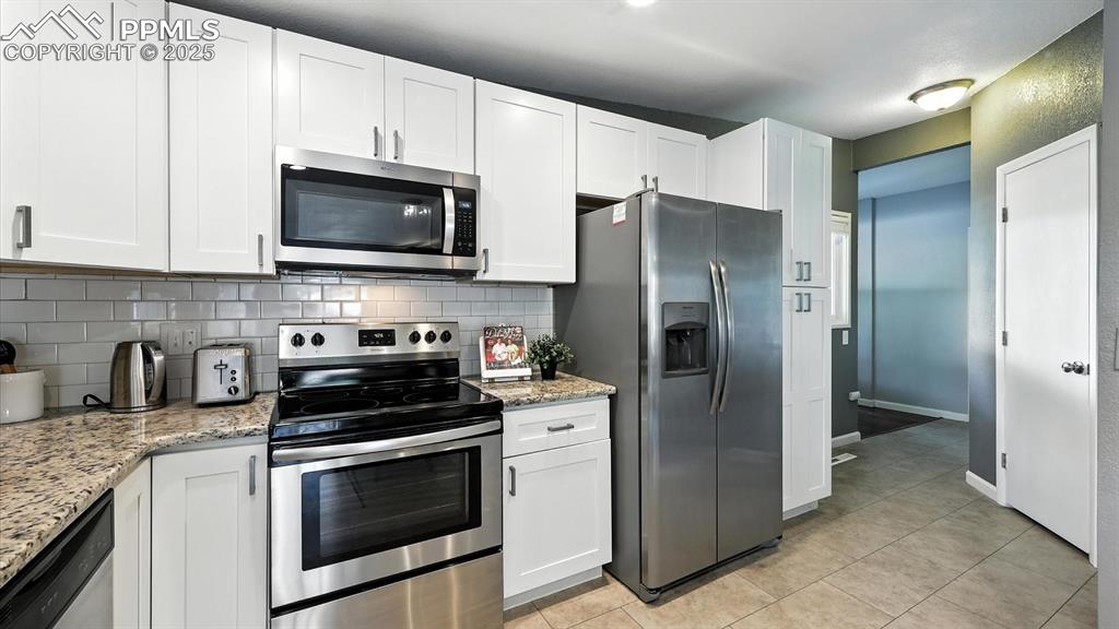 Image 7 of 35: The Kitchen features tile flooring, white cabinets with granite countertops