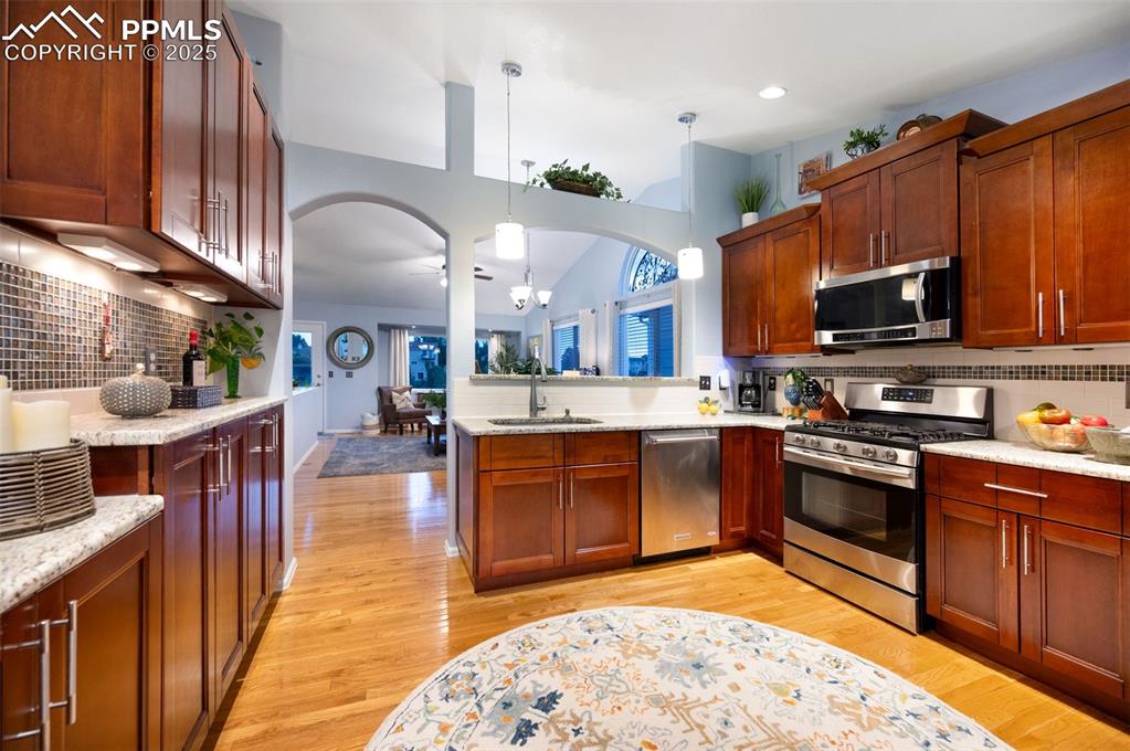 Image 10 of 49: Kitchen with backsplash, appliances with stainless steel finishes, arched w