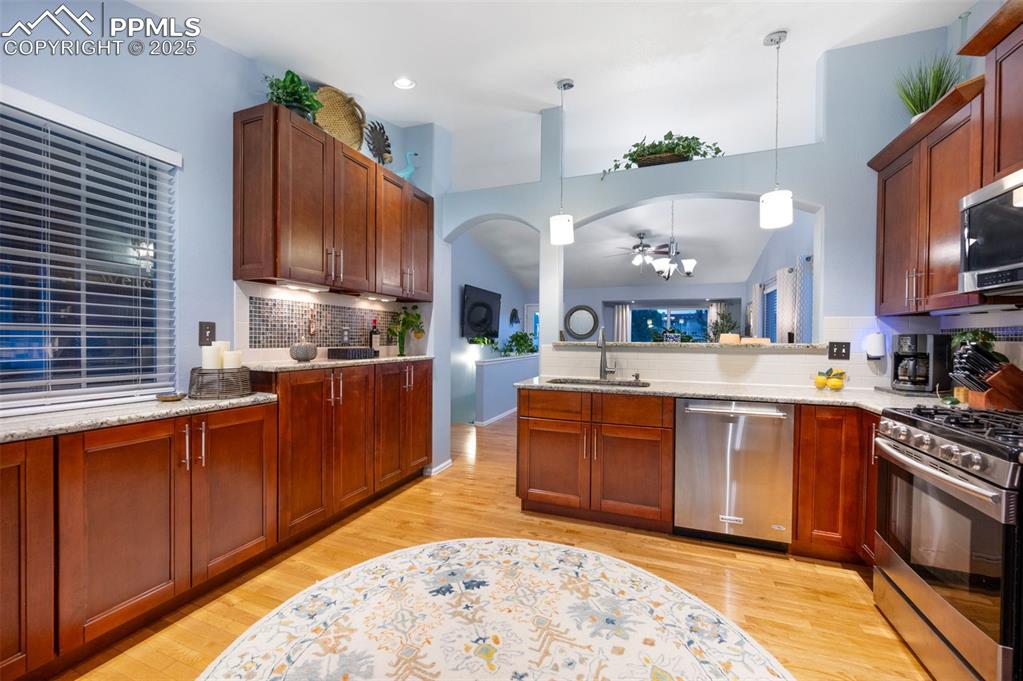 Image 11 of 49: Kitchen with tasteful backsplash, arched walkways, pendant lighting, and li