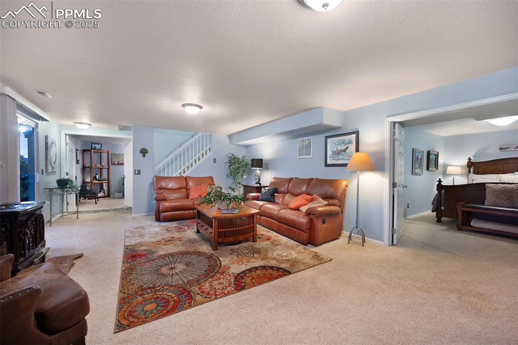 Image 24 of 49: Lower level family room with a wood stove and a walkout to stamped concrete