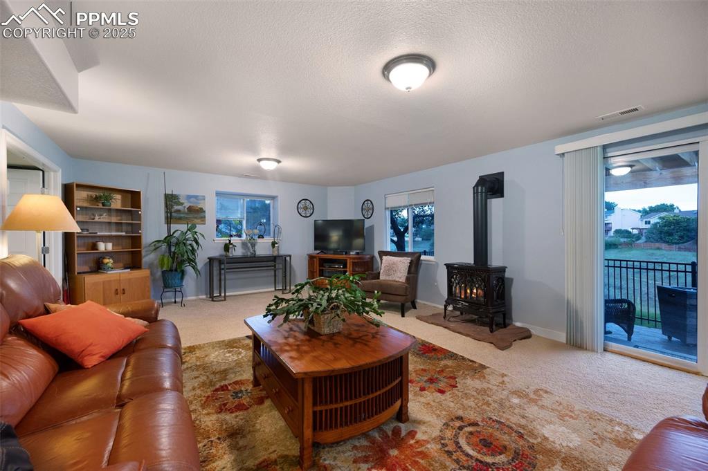 Image 25 of 49: Carpeted living room featuring a wood stove and a textured ceiling