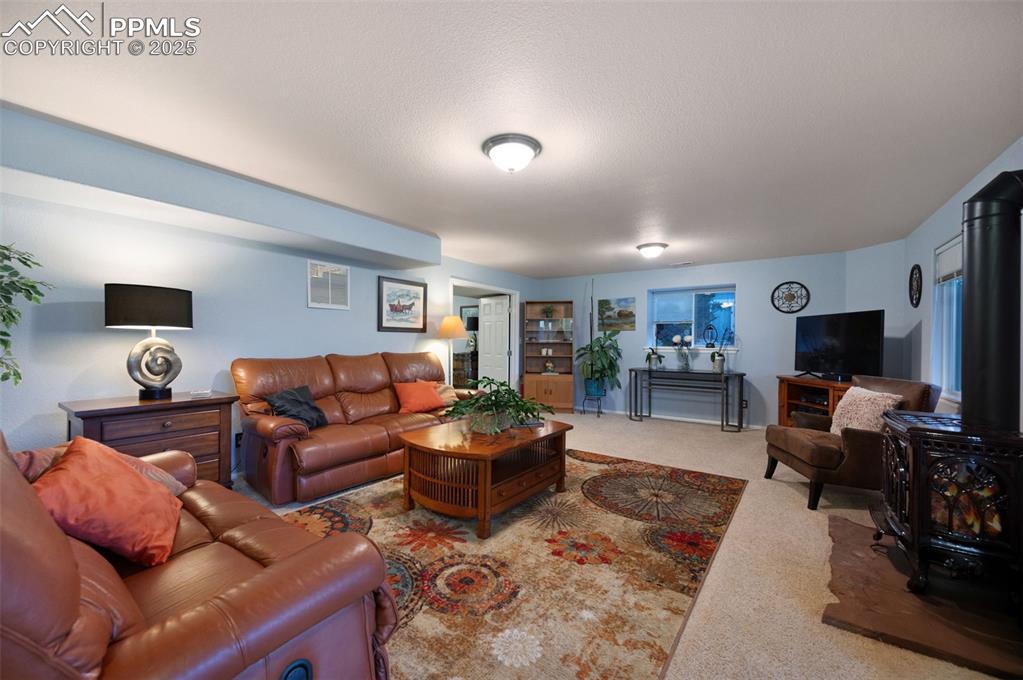 Image 26 of 49: Carpeted living room featuring a wood stove and a textured ceiling