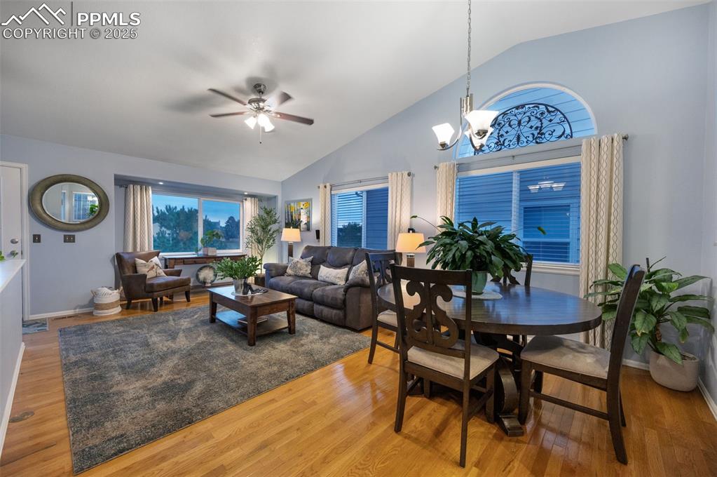 Image 4 of 49: Dining area with wood finished floors, a ceiling fan, high vaulted ceiling,
