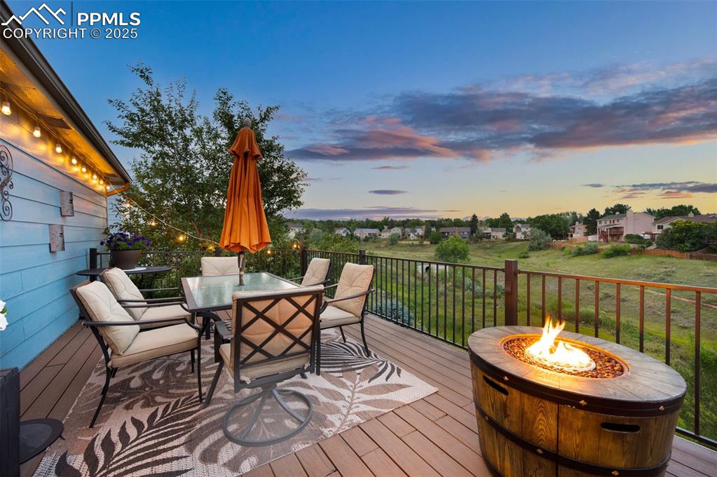Image 40 of 49: Wooden deck with outdoor dining space and an outdoor fire pit