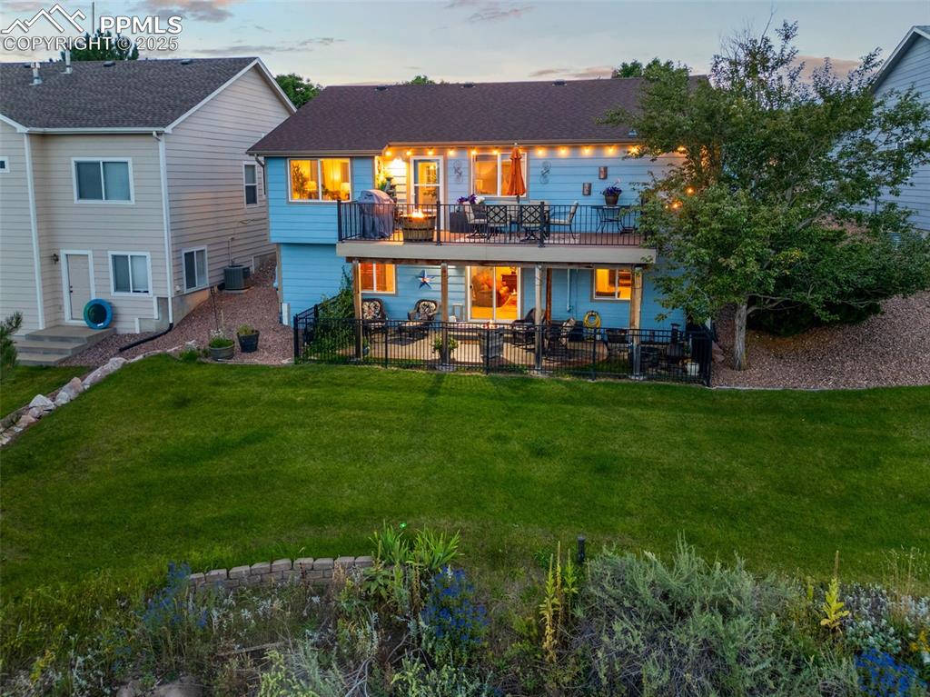 Image 43 of 49: Back of property at dusk featuring a lawn and a patio area