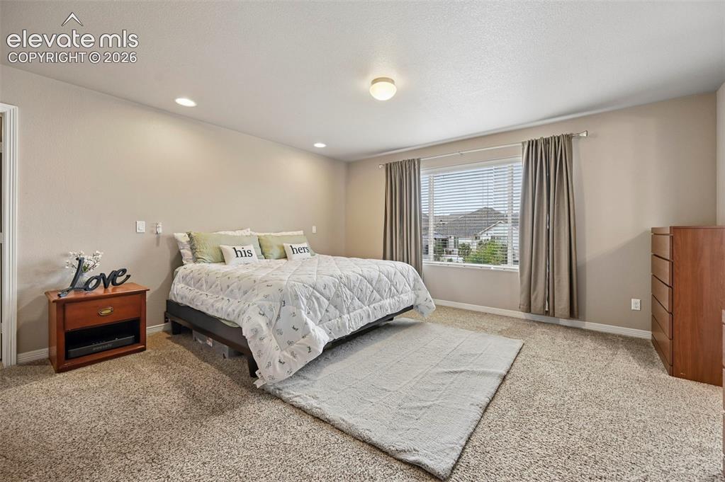 Image 13 of 24: Spacious bedroom featuring light-colored walls, recessed ceiling lighting,