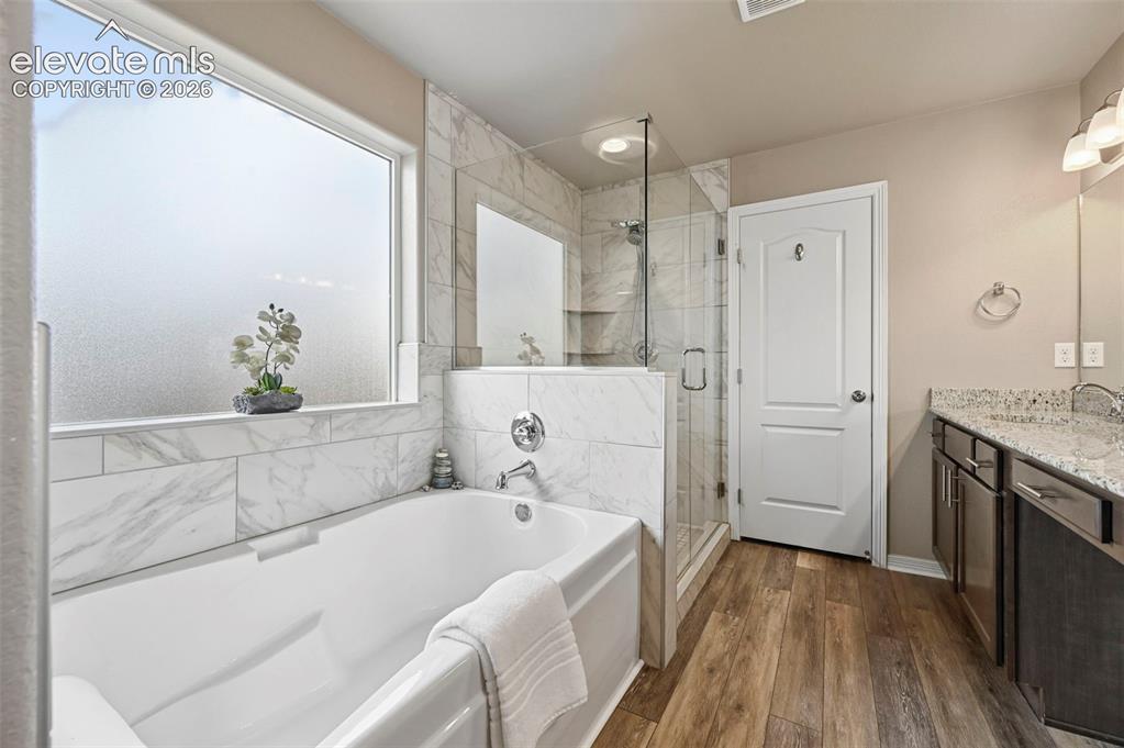 Image 15 of 24: Bathroom featuring a white soaking tub, an enclosed glass shower, and a dua