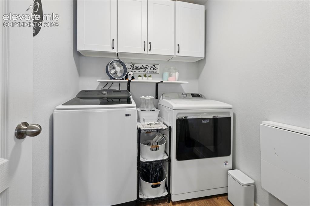 Image 17 of 24: Dedicated utility space featuring white upper cabinetry with black hardware