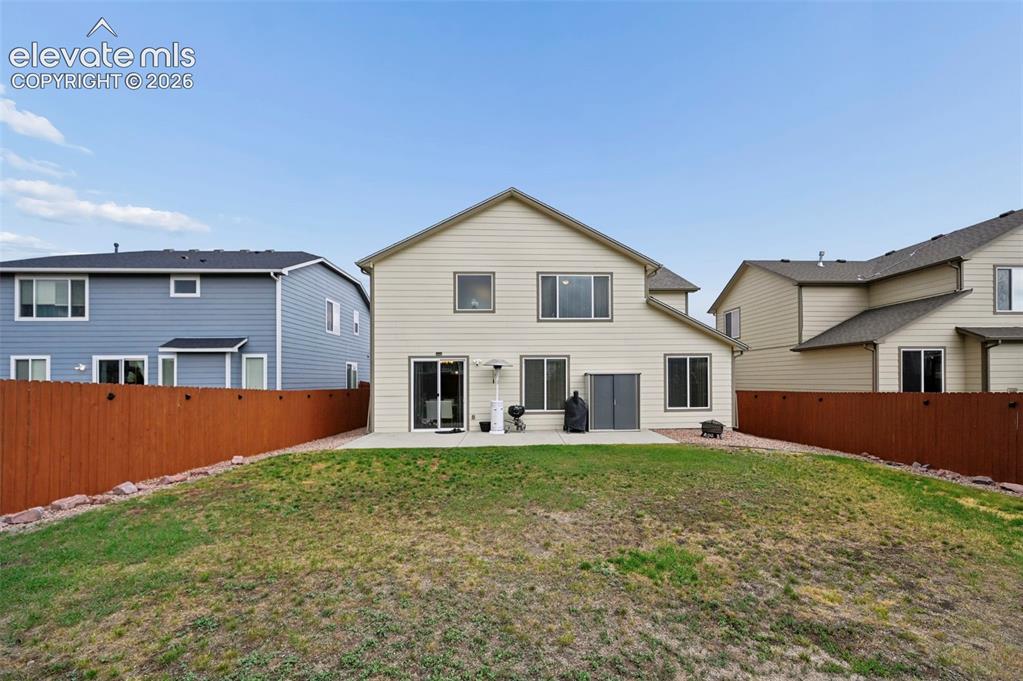Image 22 of 24: Rear exterior featuring a concrete patio, sliding glass doors, and a partia