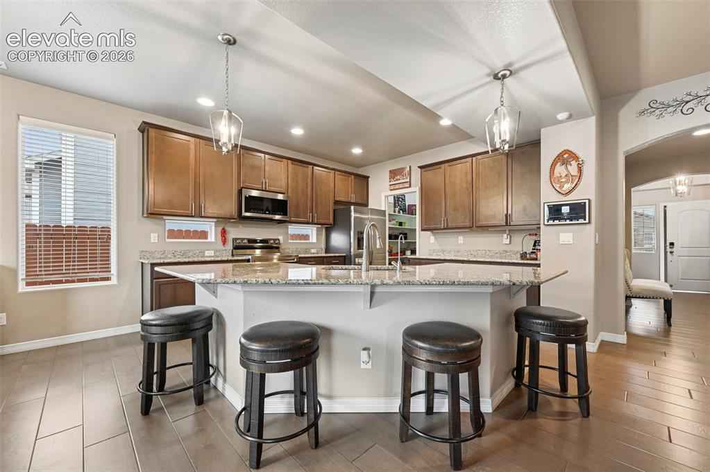 Image 3 of 24: Kitchen featuring an expansive island with seating, granite countertops, wo