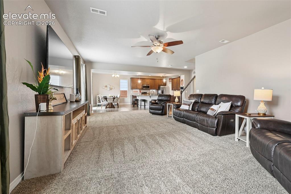 Image 4 of 24: Open-concept living space featuring neutral-toned carpeting, a ceiling fan
