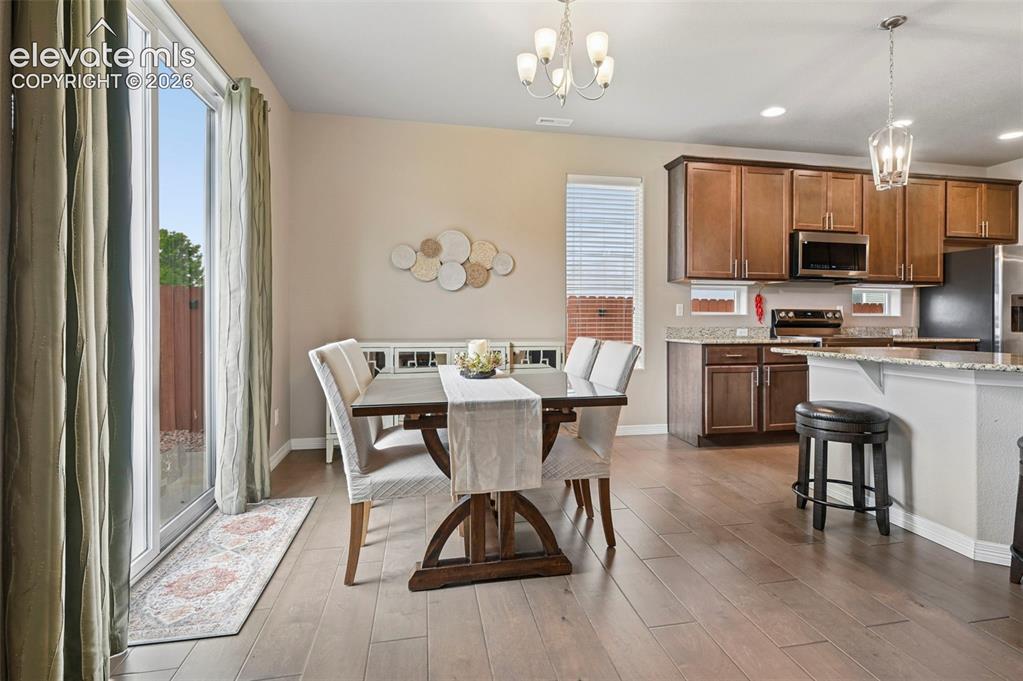 Image 7 of 24: Open-concept dining area featuring wood-finish flooring, a sliding glass do