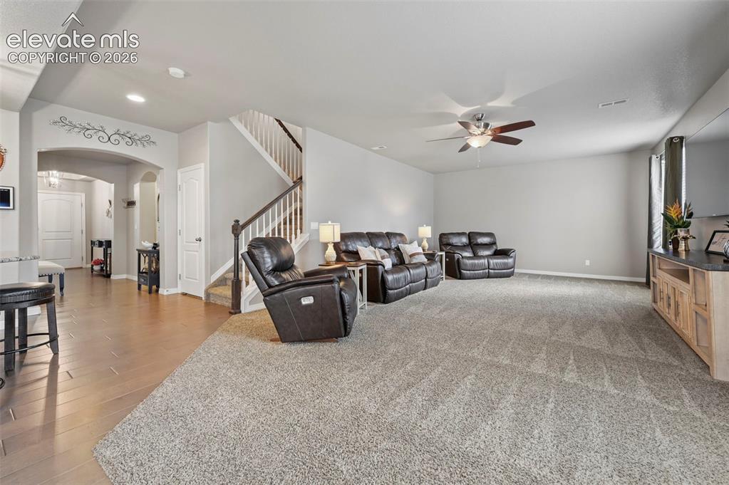 Image 9 of 24: Spacious living area featuring neutral carpeting, a ceiling fan, and recess