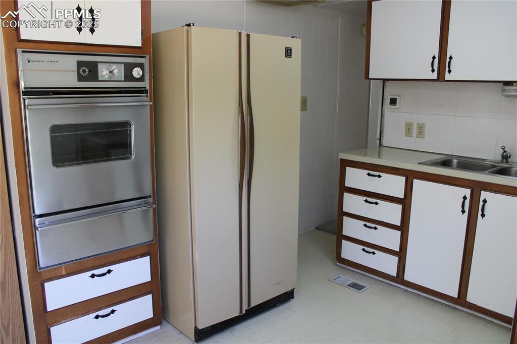 Image 10 of 20: Kitchen featuring white cabinets, freestanding refrigerator, stainless stee