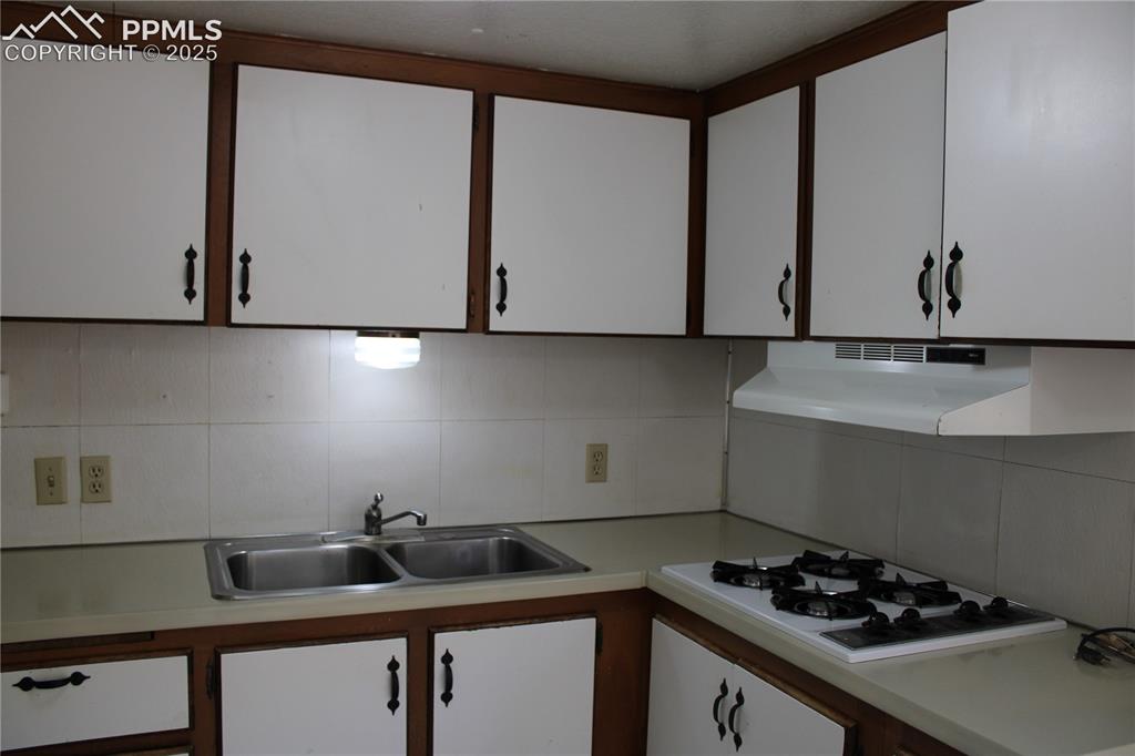 Image 8 of 20: Kitchen featuring white cabinets, light countertops, tasteful backsplash, a