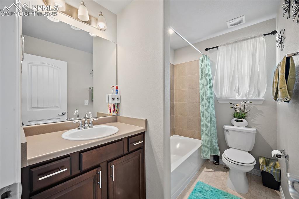 Image 17 of 36: Bathroom with vanity, shower / tub combo with curtain, and light tile patte