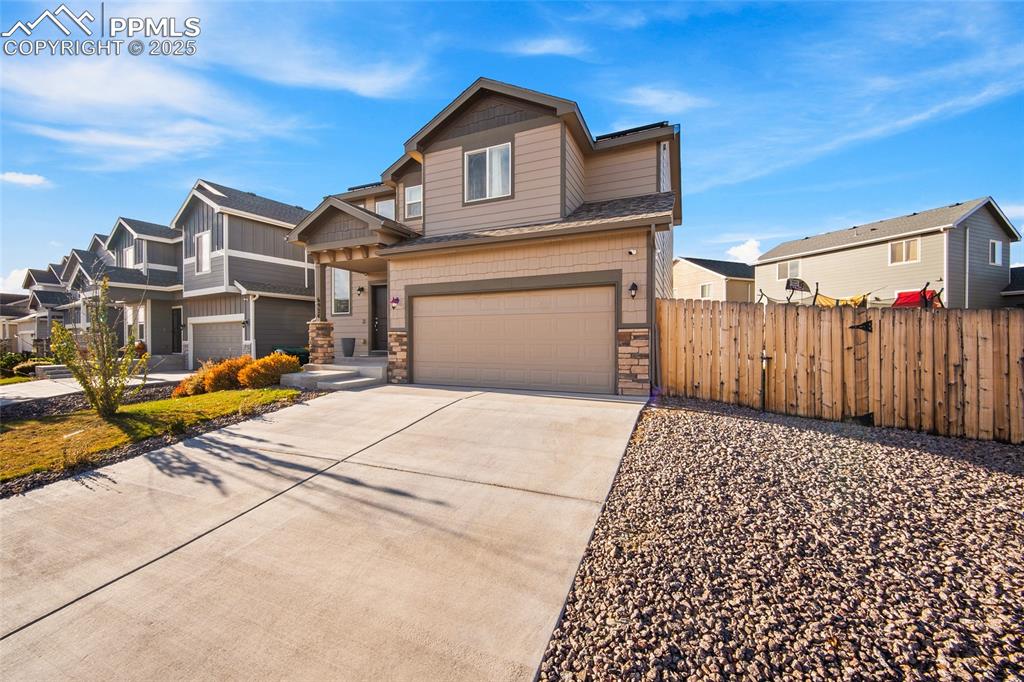 Image 2 of 36: View of front of home with stone siding, concrete driveway, an attached gar