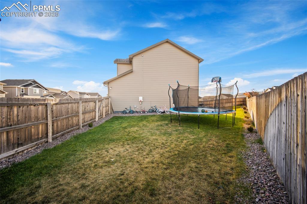 Image 32 of 36: Back of house featuring a fenced backyard and a trampoline