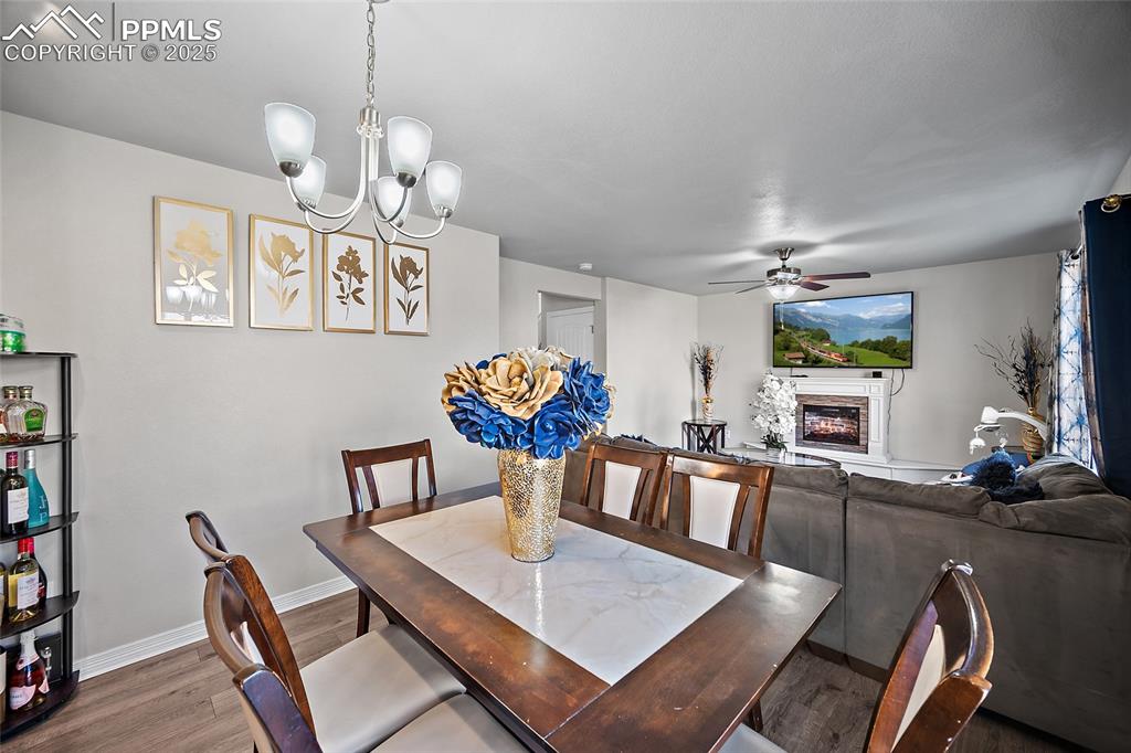 Image 6 of 36: Dining space with a glass covered fireplace, wood finished floors, a chande