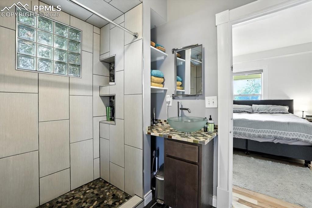 Image 10 of 48: Full bathroom with a shower stall, vanity, ensuite bath, and wood finished 