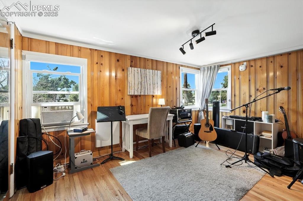 Image 12 of 48: Home office featuring wood walls, light wood-type flooring, and cooling uni