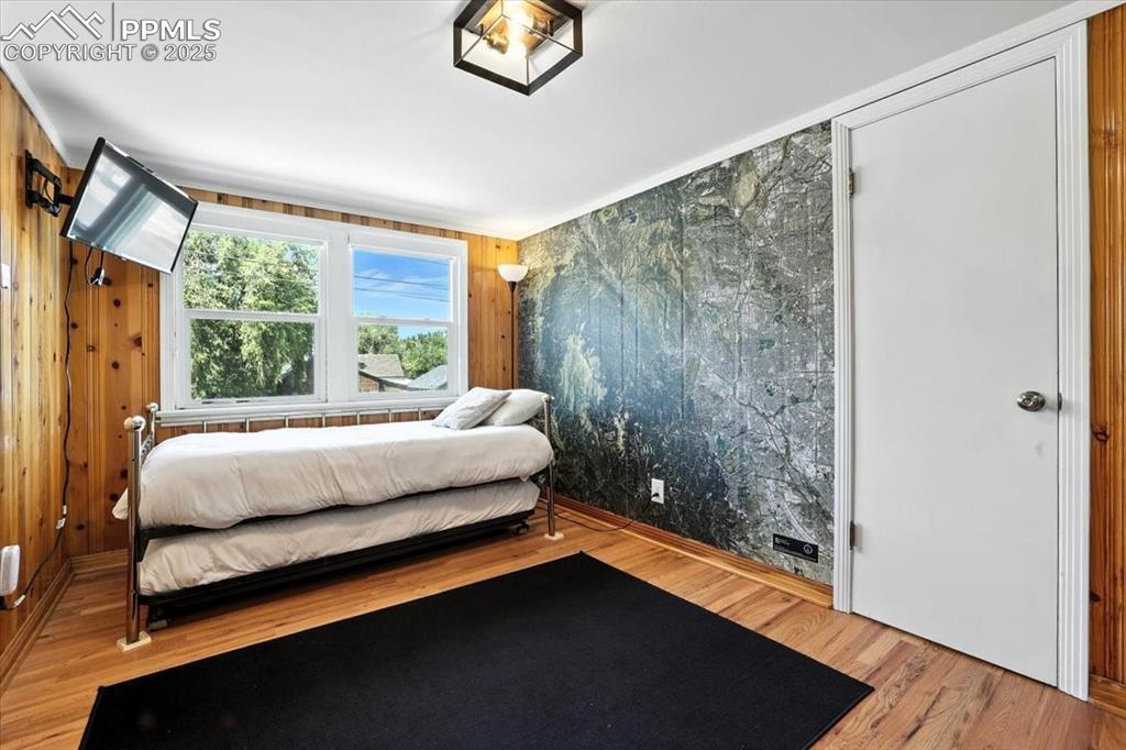 Image 13 of 48: Bedroom featuring light wood-type flooring and wooden walls