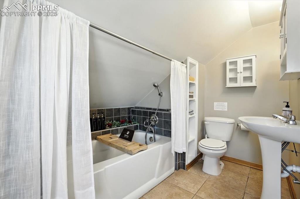 Image 14 of 48: Full bath featuring lofted ceiling, shower / tub combo, and light tile patt