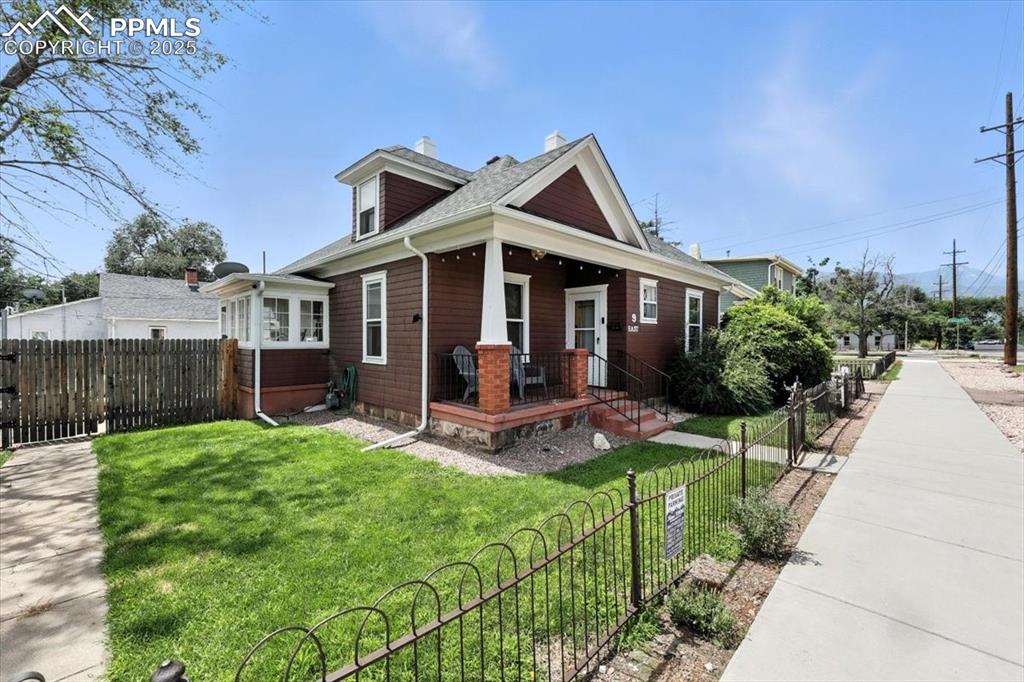 Image 18 of 48: View of front of house with a fenced front yard, covered porch, a chimney, 