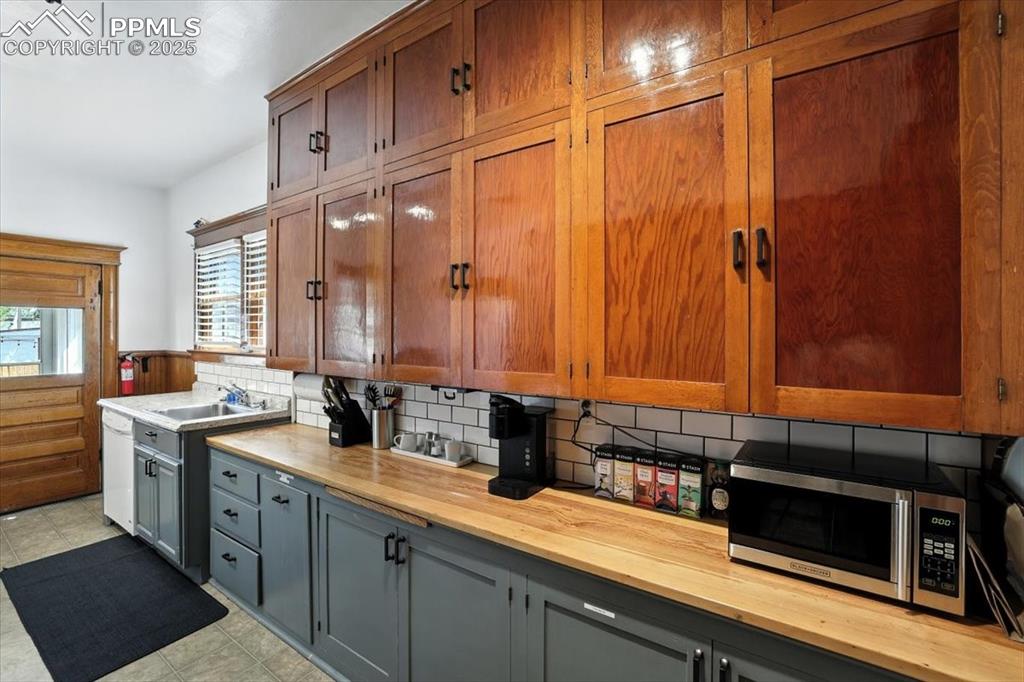 Image 26 of 48: Kitchen with wooden counters, decorative backsplash, stainless steel microw