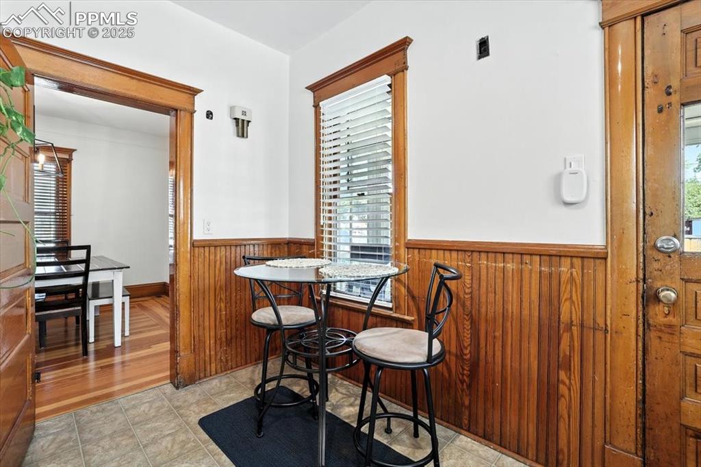 Image 27 of 48: Dining room featuring a wainscoted wall, light tile patterned flooring, and