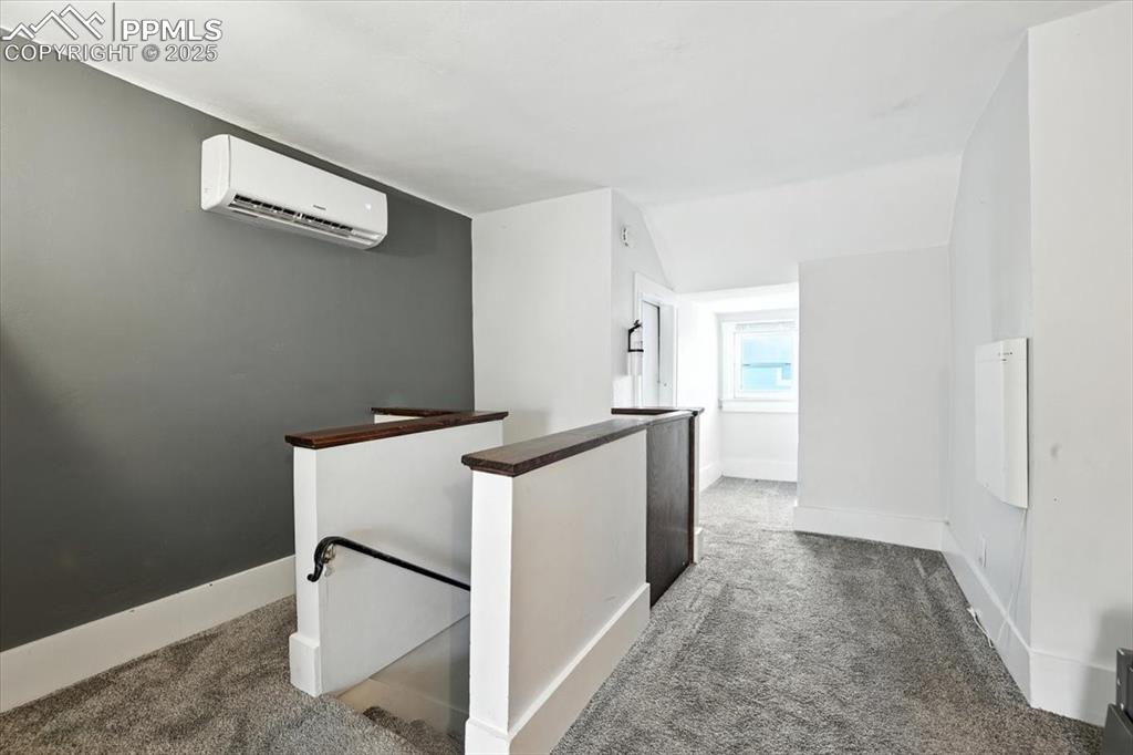 Image 31 of 48: Hall featuring an upstairs landing, dark carpet, an AC wall unit, and lofte