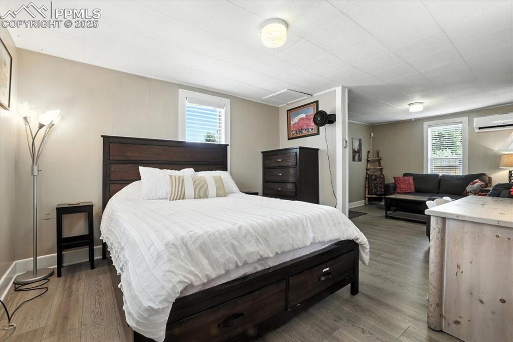 Image 38 of 48: Bedroom featuring light wood-style flooring, multiple windows, and an AC wa