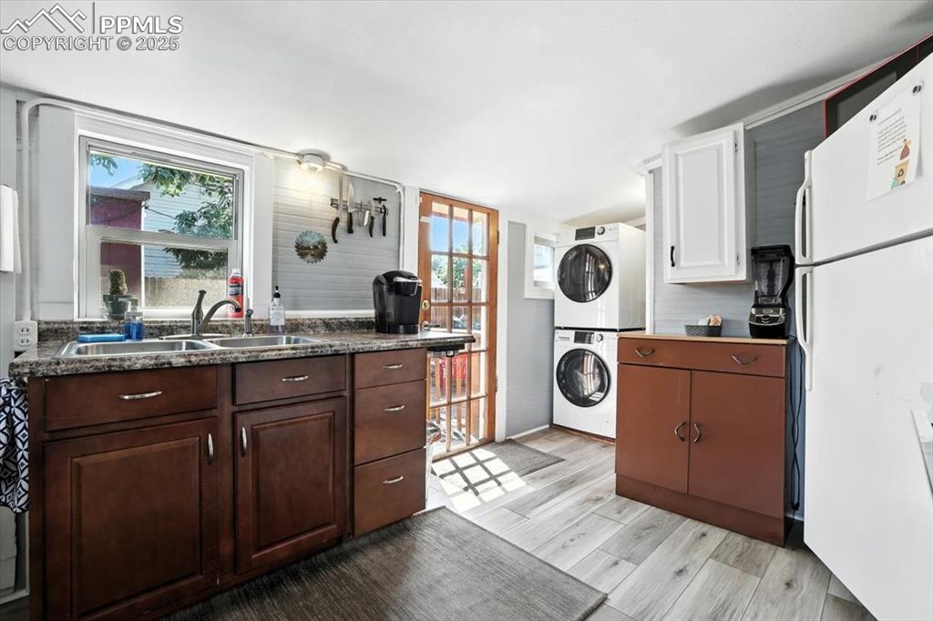 Image 40 of 48: Kitchen with freestanding refrigerator, dark countertops, light wood-style 