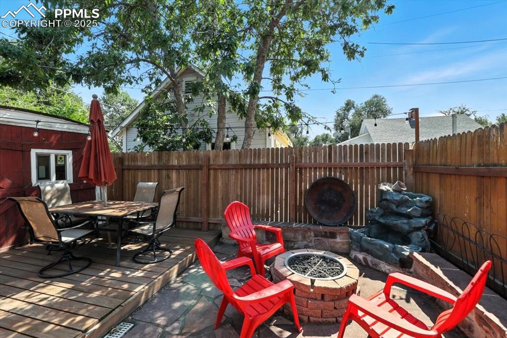 Image 43 of 48: Fenced backyard with an outdoor fire pit, outdoor dining space, a deck, and