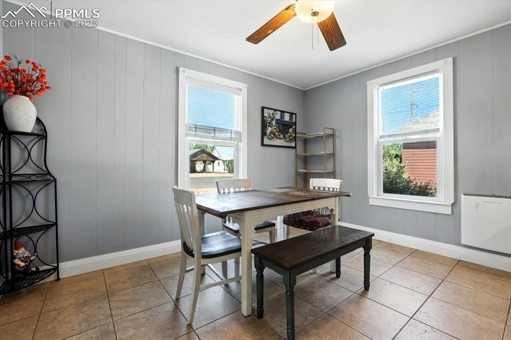 Image 8 of 48: Dining space featuring wood walls, ornamental molding, light tile patterned