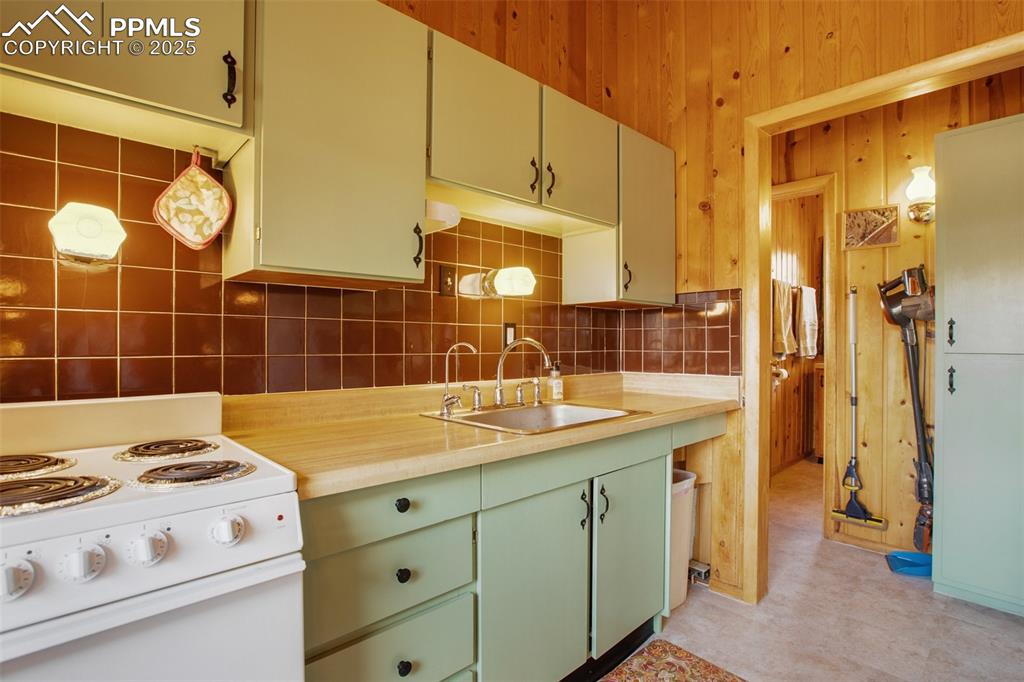 Image 10 of 38: Kitchen featuring light countertops, a sink, backsplash, and white electric