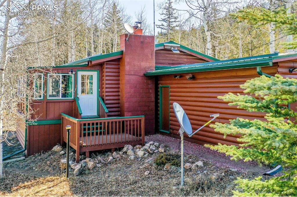 Image 2 of 38: Rear view of property featuring a chimney and metal roof