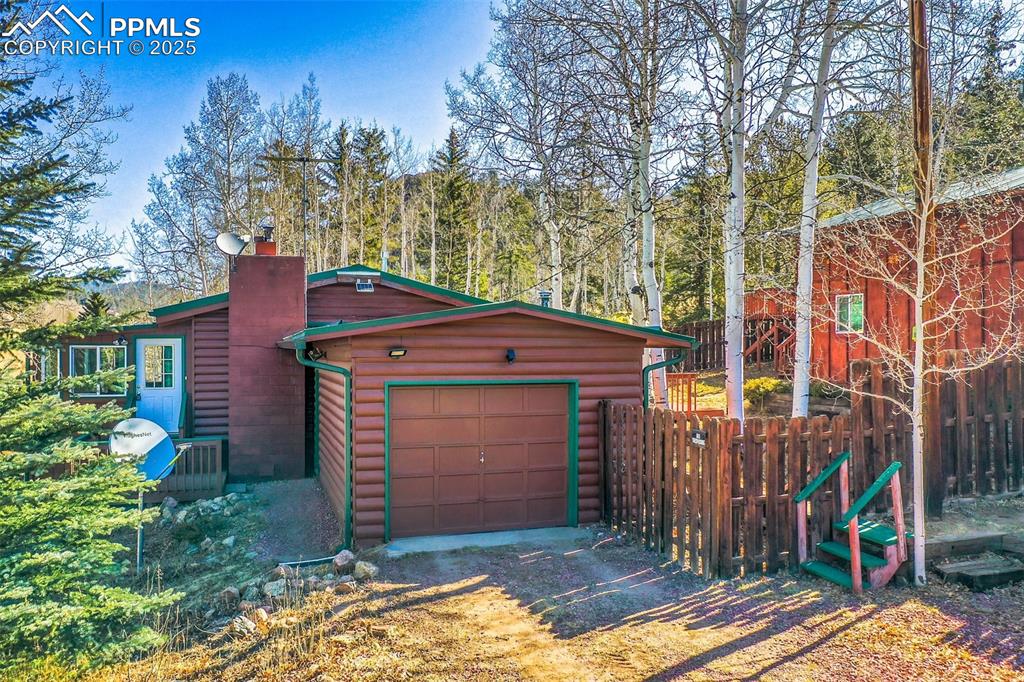 Image 4 of 38: Garage with fence and dirt driveway