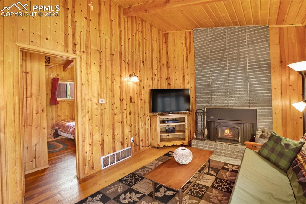 Image 6 of 38: Living room with beamed ceiling, wood ceiling, wood finished floors, and wo